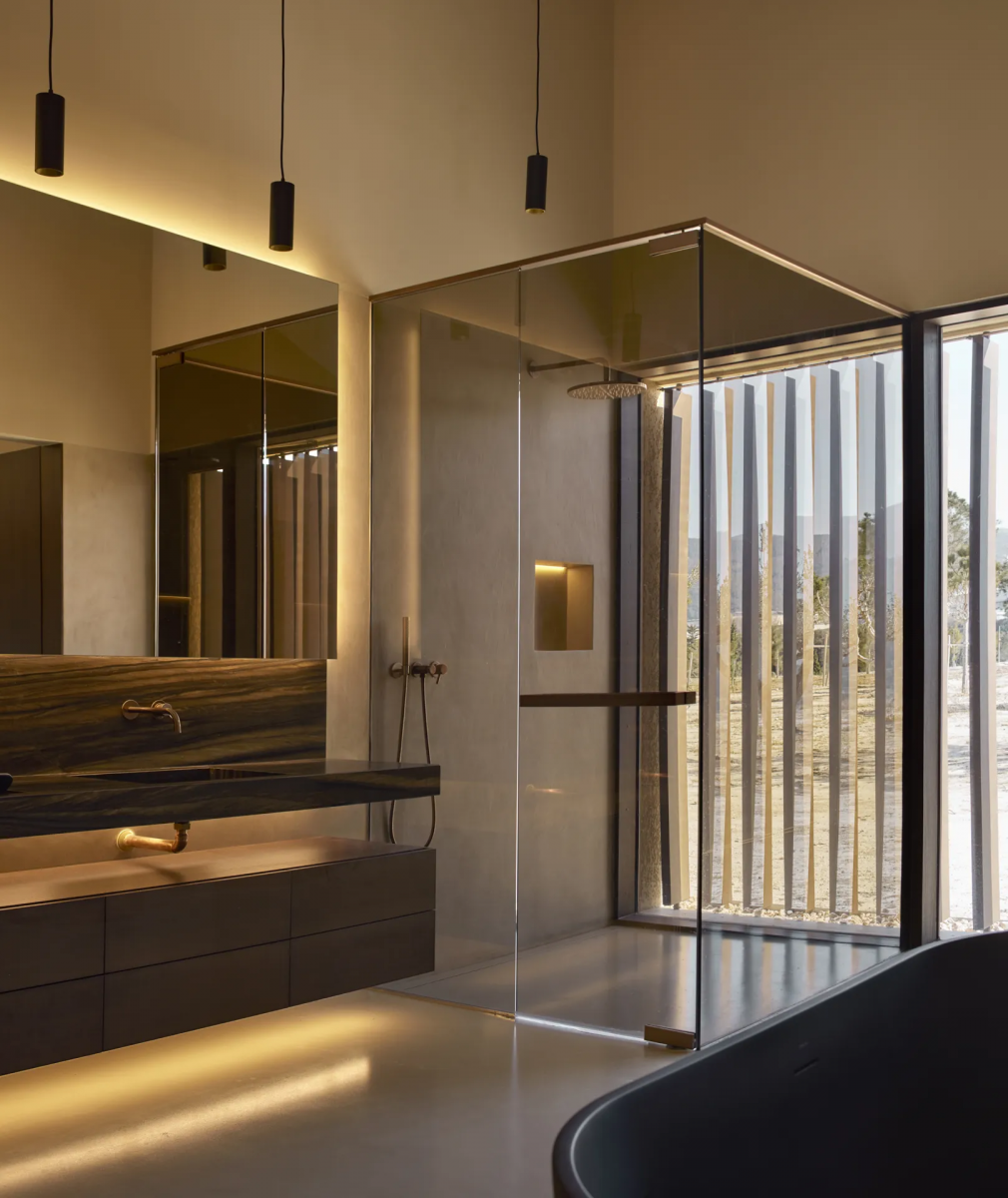 Baño con iluminación cálida, suelo de revestimiento continuo Bullconcept Hybrid y paredes revestidas con microcemento