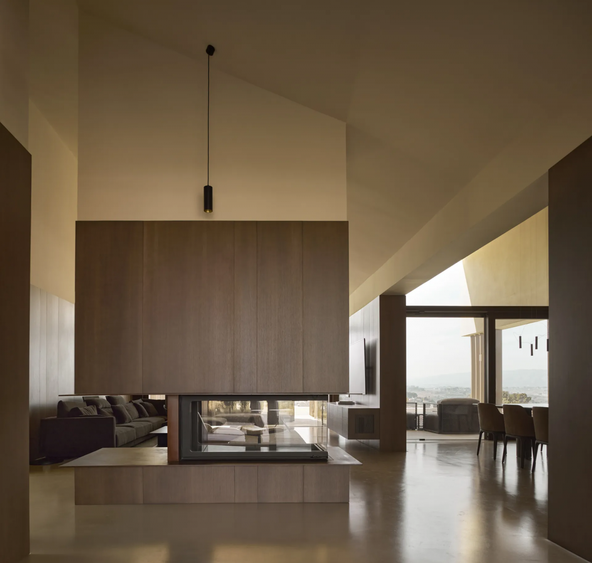 Salón amplio con chimenea central y suelo de revestimiento continuo Bullconcept Hybrid que unifica toda la vivienda